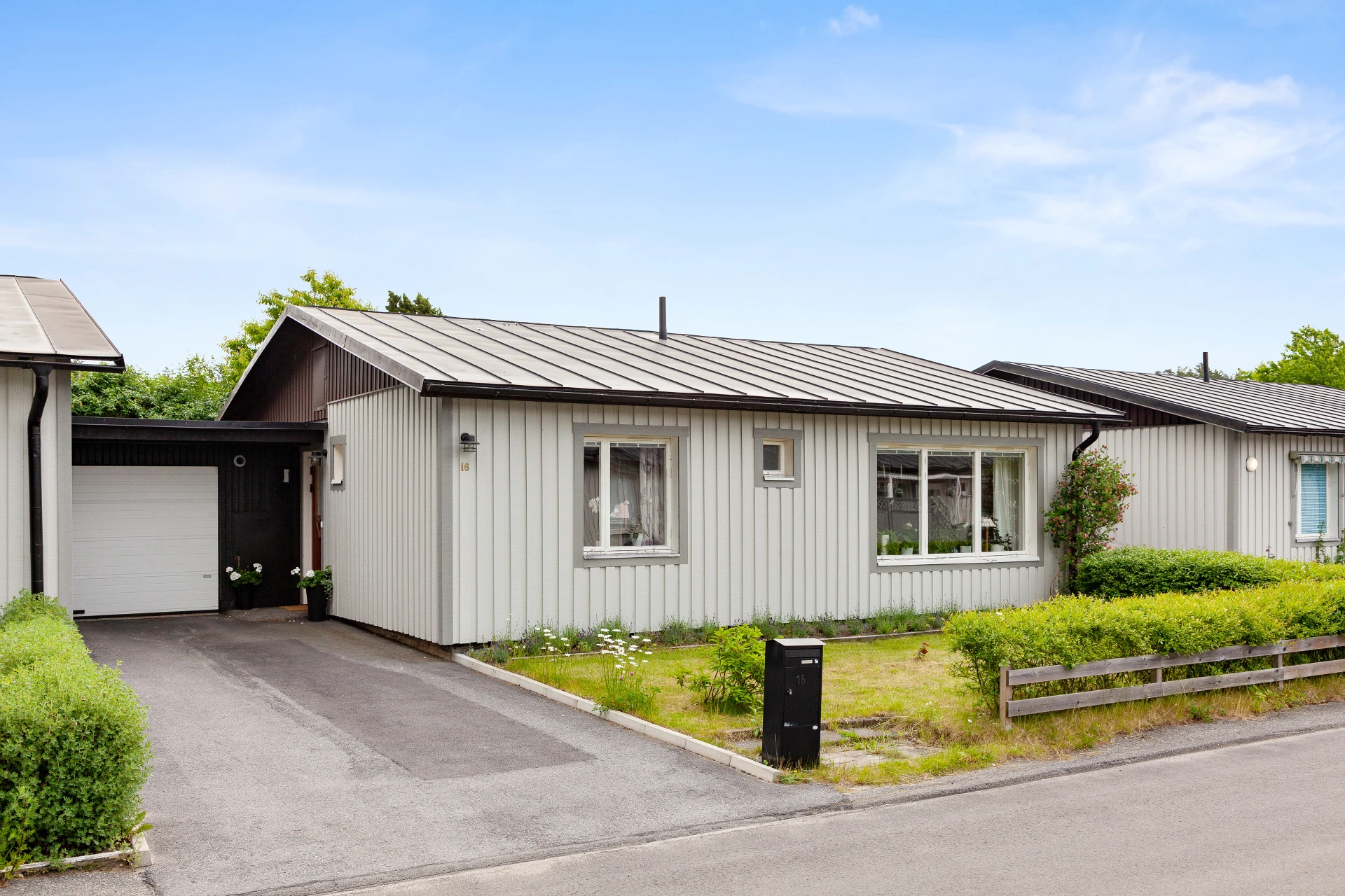 Framsida med uppfart, garage och gräsmatta