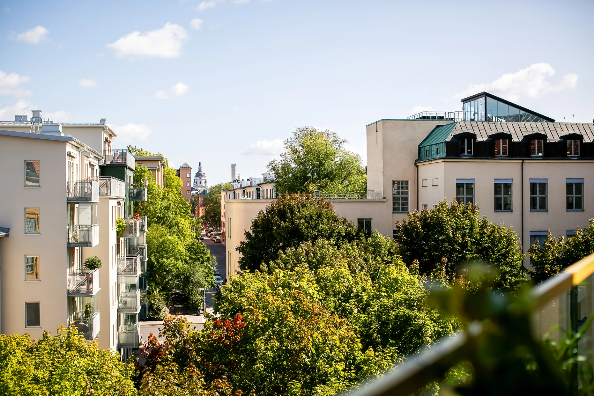  Den lummiga förgreningsgatan är kantad av träd, med Söders vackra hus och kyrktorn i horisonten